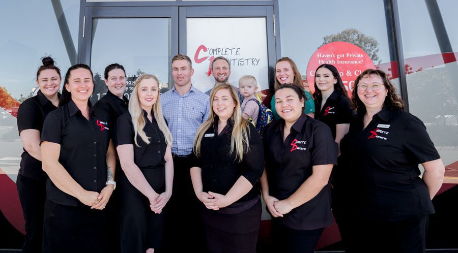 Team of dentists in front of business store front